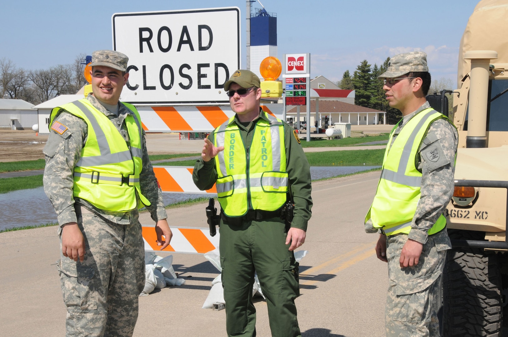 U.S. Customs and Border Patrol agent Collin Blackwell, center, discusses tactics with U.S. Army Soldiers, from left to right, Spc. Brandon Nelson and Spc. Fredrick Burdick, both of the 3662nd Maintenance Company, North Dakota Army National Guard, at a traffic control point on the outskirts of Cavalier, N.D.