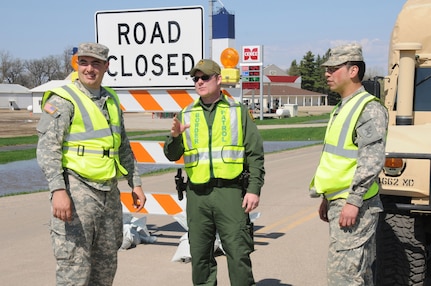 U.S. Customs and Border Patrol agent Collin Blackwell, center, discusses tactics with U.S. Army Soldiers, from left to right, Spc. Brandon Nelson and Spc. Fredrick Burdick, both of the 3662nd Maintenance Company, North Dakota Army National Guard, at a traffic control point on the outskirts of Cavalier, N.D.