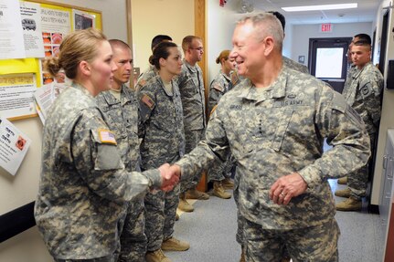 Gen. Frank J. Grass, shakes hands June 11, 2013, with Spc. Kristen Croymans, a medic with the 730th Area Support Medical Company, South Dakota Army National Guard, during his visit to Lower Brule, S.D., as a part the 29th annual Golden Coyote training exercise.