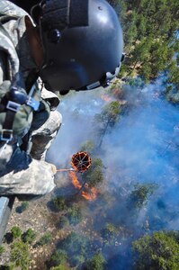 Fires are keeping components of the Colorado National Guard busy. In this June 12, 2013, image, Colorado Army National Guard Staff Sgt. Edwin Wiley directs a bucket drop on the Black Forest Fire from a UH-60 Black Hawk helicopter, in El Paso County, Colo.