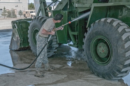 Staff Sgt. Brent Peden, a surface maintenance mechanic at the Combined Support Maintenance Shop in Carson City, Nev., uses the new Net Zero Heavy Solids Wash Rack cannon to remove debris from a front loader before conducting a maintenance check.