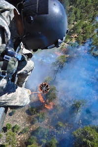 Fires are keeping components of the Colorado National Guard busy. In this June 12, 2013, image, Colorado Army National Guard Staff Sgt. Edwin Wiley directs a bucket drop on the Black Forest Fire from a UH-60 Black Hawk helicopter, in El Paso County, Colo.