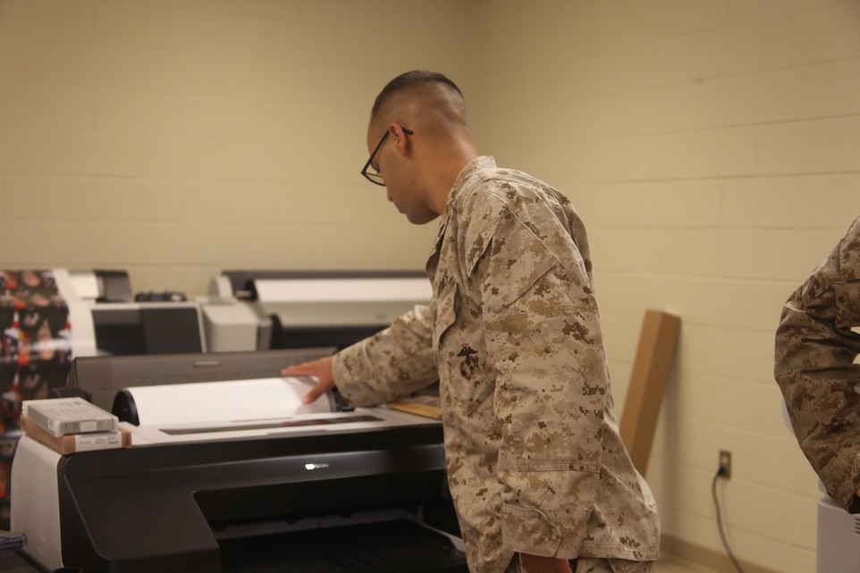 Cpl. Hector L. Dejesus, a combat videographer with Station Combat Camera, checks on a printer in his shop Tuesday.