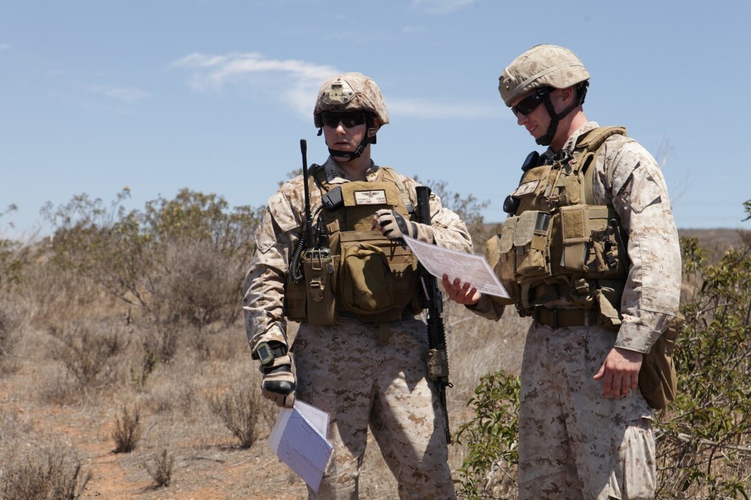 Capt. Colin Culkin, firepower control team leader reviews a map of targets with Capt. Robert Wells, exercise control, during a communication exercise between FCTs on Camp Pendleton, Calif., Aug. 8. Understanding the language of the Air Naval Gunfire Liaison Company involves mastering multiple acronyms and radio operating procedures to help firepower control teams communicate targets to pilots during missions.