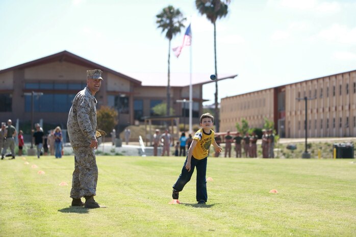 First Sgt. Kevin Bowman, company first sergeant, Headquarters and Service Company, 1st Light Armored Reconnaissance Battalion, watches his son James throw a training grenade during the battalion's Bring Your Kids to Work Day at Camp Las Flores here, Aug. 9, 2013. Highlanders, the battalion's nickname, and their children participated in field games such as the egg toss, three-legged race, tug of war and a modified version of the Combat Fitness Test during the family day event. Bowman is a native of North Tonawanda, N.Y.