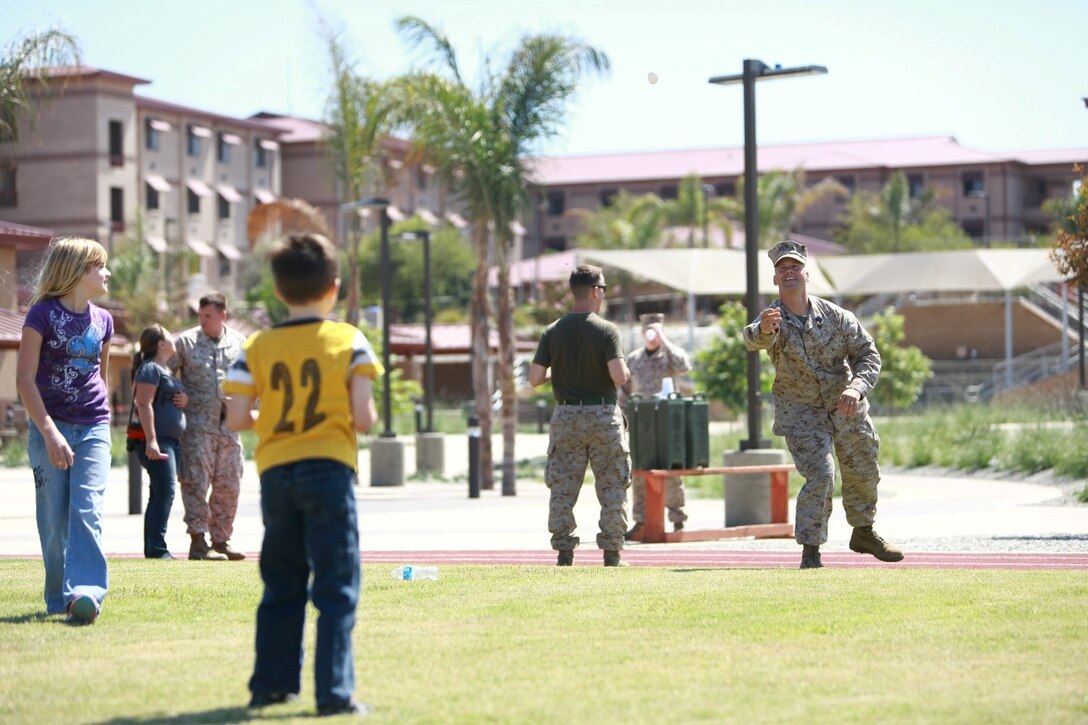 First Sgt. Kevin Bowman, company first sergeant, Headquarters and Service Company, 1st Light Armored Reconnaissance Battalion, plays a game of egg toss with his son James during the battalion's Bring Your Kids to Work Day at Camp Las Flores here, Aug. 9, 2013. Highlanders, the battalion's nickname, and their children participated in field games such as the egg toss, three-legged race, tug of war and a modified version of the Combat Fitness Test during the family day event. Bowman is a native of North Tonawanda, N.Y.