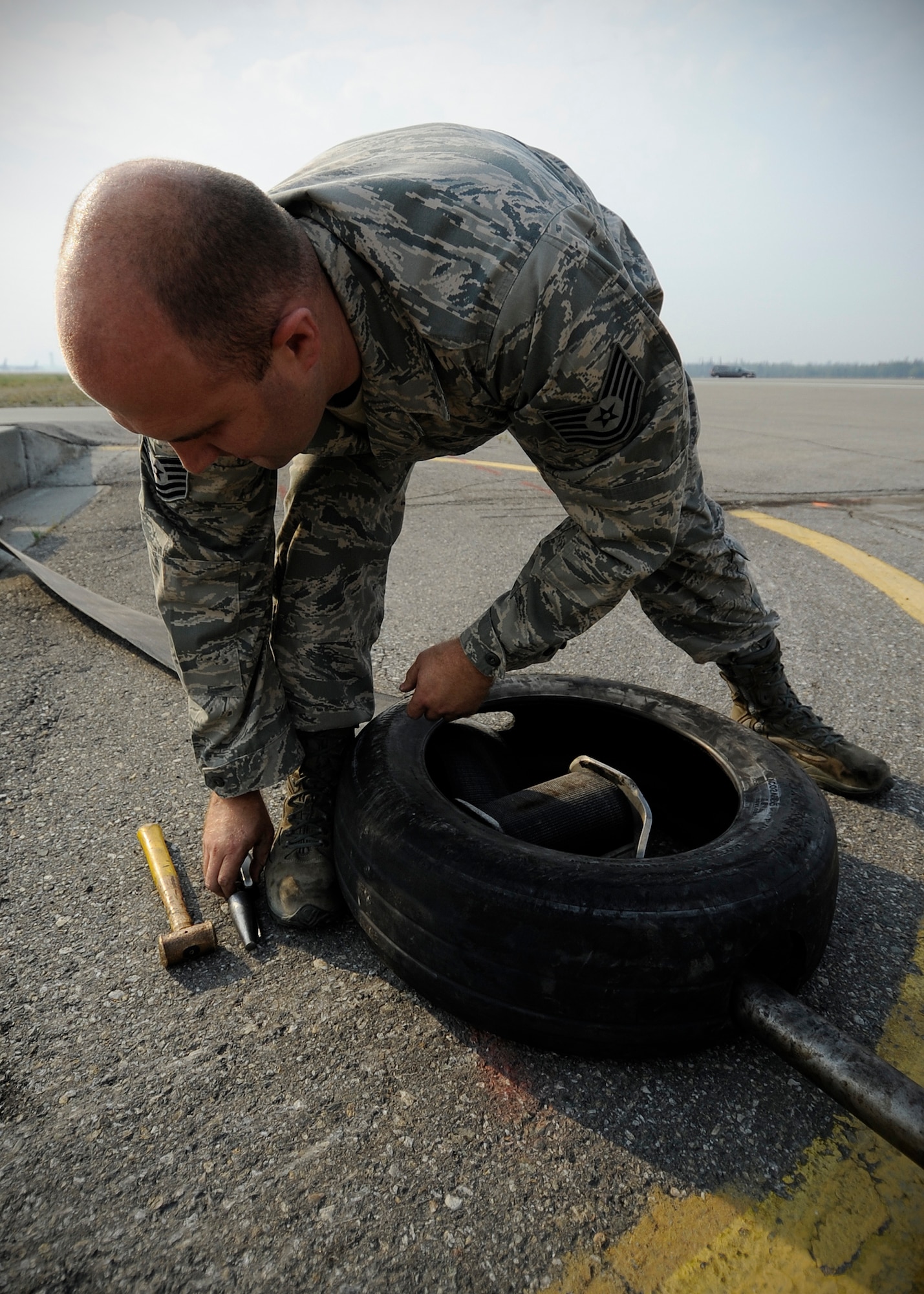 Tech. Sgt. Brian Brown, 354th Civil Engineer Squadron power production NCO in charge, adjusts a disk system, which connects a 1.25 inch cable to a six-inch thick 1,600 foot long nylon strap on the flight line during RED FLAG-Alaska 13-3 Aug. 14, 2013, Eielson Air Force Base, Alaska. The cable system is used in case of emergency landing when an aircraft needs to make an abrupt stop. (U.S. Air Force photo by Senior Airman Shawn Nickel/Released)