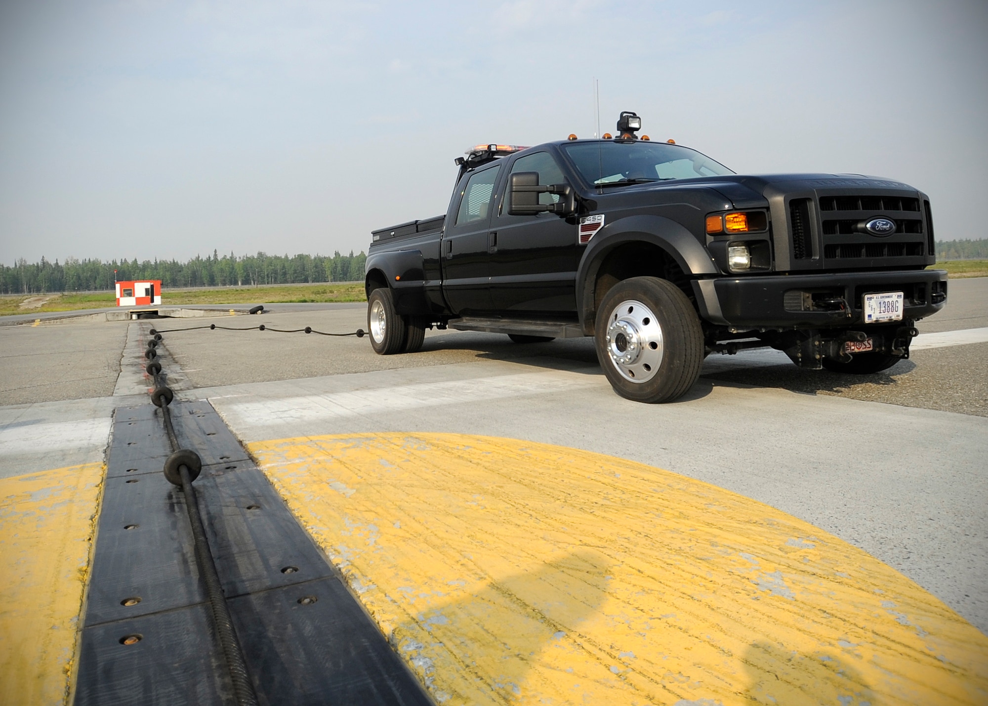 Sonny Hill, 354th Civil Engineer Squadron power production technician, drags a cable from the runway during RED FLAG-Alaska 13-3 Aug. 14, 2013, Eielson Air Force Base, Alaska. The  cable is part of the barrier aircraft arresting kit cable systems, which acts as an emergency brake for a troubled aircraft which may be having trouble on  landing. (U.S. Air Force photo by Senior Airman Shawn Nickel/Released)