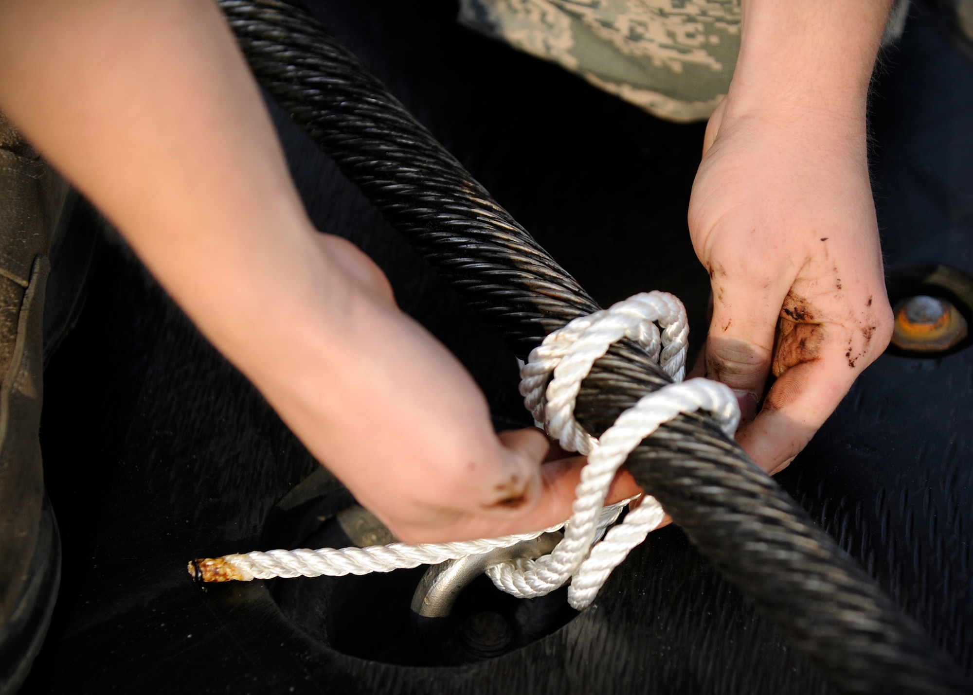 Airman 1st Class Nathan Miles, 354th Civil Engineer Squadron power production technician, uses rope to keep a 303 foot 1,600 pound steel cable, part of the barrier aircraft arresting kit cable systems, in place on the flight line during RED FLAG-Alaska 13-3 Aug. 14, 2013, Eielson Air Force Base, Alaska. Participating airframes can often be low to the ground, so the team makes sure the steel length is secured inches off the ground. (U.S. Air Force photo by Senior Airman Shawn Nickel/Released)