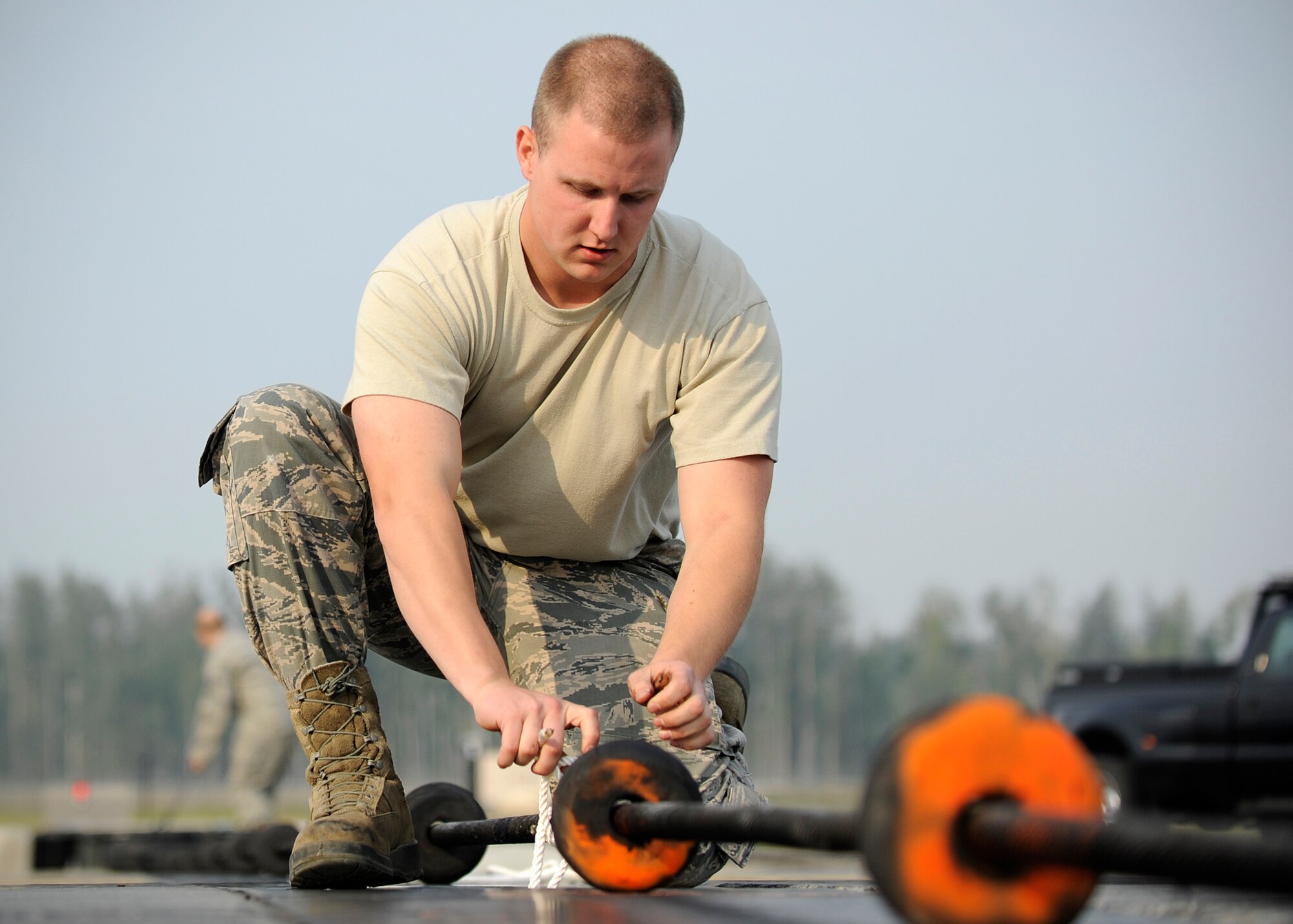 Airman 1st Class Nathan Miles, 354th Civil Engineer Squadron power production technician, uses rope to keep a 303 foot 1,600 pound steel cable, part of the barrier aircraft arresting kit cable systems, in place on the flight line during RED FLAG-Alaska 13-3 Aug. 14, 2013, Eielson Air Force Base, Alaska. Participating airframes can often be low to the ground, so the team makes sure the steel length is secured inches off the ground. (U.S. Air Force photo by Senior Airman Shawn Nickel/Released)