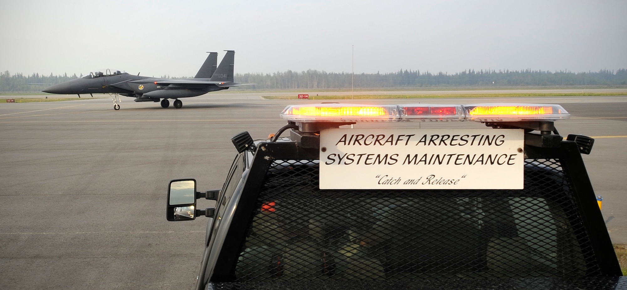 Airmen from the 354th Civil Engineer Squadron power production shop wait for air traffic to pass on the flight line Aug. 14, 2013, Eielson Air Force Base, Alaska. The 354th Civil Engineer Squadron power production shop, or Power Pros, maintains the barrier aircraft arresting kit cable systems, which acts as an emergency brake for a troubled aircraft which may be having trouble on landing. (U.S. Air Force photo by Senior Airman Shawn Nickel/Released)