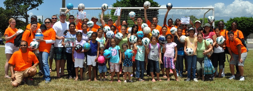 Joint Task Force-Bravo service members take a group photo for Fiesta Day with a local girls’ orphanage here before starting the day’s activities Aug 10, 2013. The JTF-Bravo’s Medical Element joined with “Kick for Nick,” a nonprofit organization, to hold a Fiesta Day, during the event, more than 75 girls from a local orphanage received more than 35 soccer balls donated by the organization, while also participating in other activities. (Photo released by U.S. Air Force Staff Sgt. Jarrod Chavana)