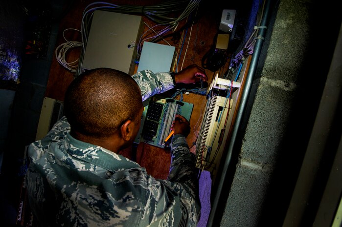 Staff Sgt. Spenser Amos, 628th Communications Squadron cyber transport systems technician, wires phone lines to a number block during a trouble ticket call Aug. 8, 2013, at Joint Base Charleston - Air Base, S.C. The infrastructure flight maintains all communications cabling which includes copper wiring, inside building cabling, outside building cabling, all telephone switches to include two main systems on the Weapons Station and four main systems on the Air Base for voice systems, as well as a 400 device data network between both sides of the base for more than 200 buildings. (U.S. Air Force photo/ Senior Airman George Goslin)
