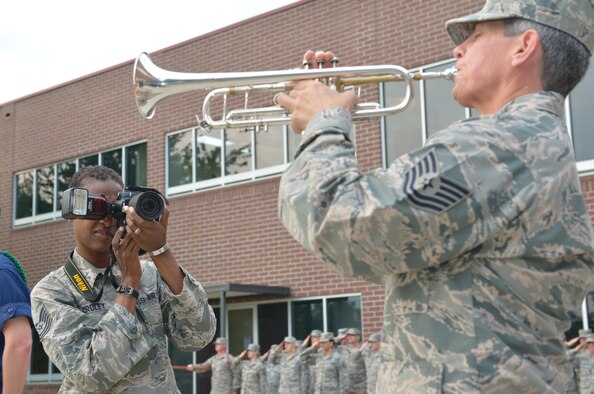 MCGHEE TYSON AIR NATIONAL GUARD BASE, Tenn. - Tech. Sgt. Lakisha Croley, Air Force photographer, 1st Combat Camera Squadron at Joint Base Charleston in South Carolina, photographs bugler Tech. Sgt. Cheryl A. Przytula from the 139th Logistics Readiness Squadron from Missouri during morning reveille at the I. G. Brown Training and Education Center, Aug. 14, 2013. Both Croley and Przytula are attending the Noncommissioned Officer Academy here. (U.S. Air National Guard photo by Master Sgt. Kurt Skoglund/Released)