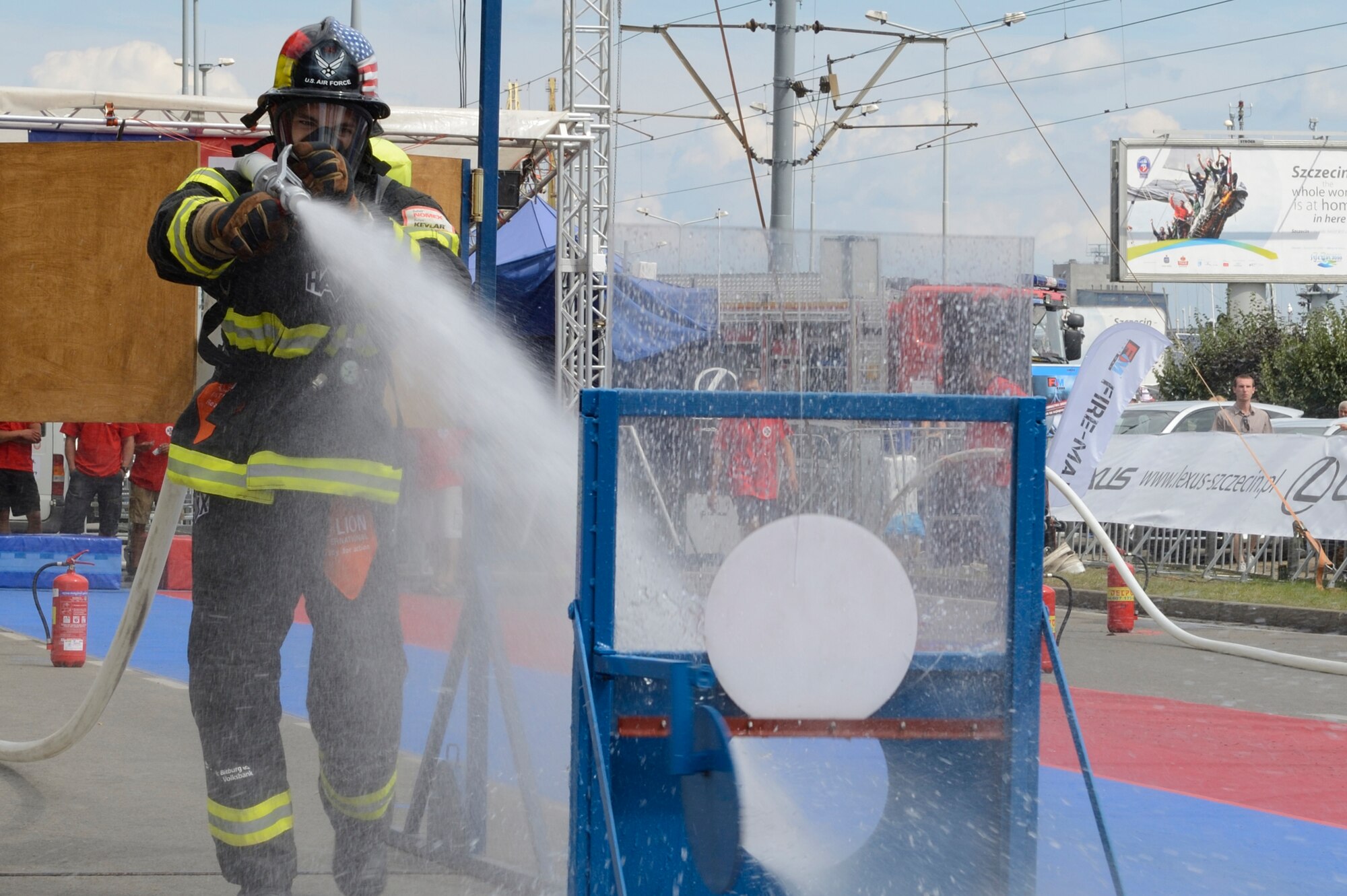 SPANGDAHLEM AIR BASE, Germany – U.S. Air Force Staff Sgt. Benjamin Gonsales, 52nd Civil Engineer Squadron firefighter from Savannah, Ga., sprays water to extinguish a simulated fire at the Szczecin Firefighter Combat Challenge in Szczecin, Poland Aug. 10, 2013. Gonsales carried the hose a distance of 78 feet, turning on the hose to extinguish the fire after crossing a simulated door to a building. (U.S. Air Force photo by Staff Sgt. Christopher Ruano/Released)