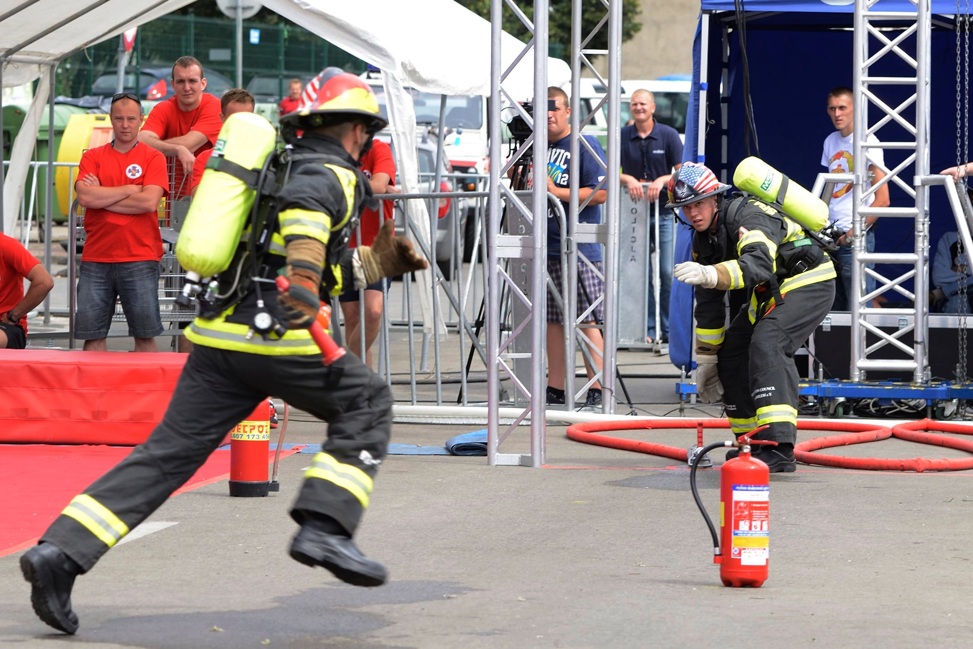 SPANGDAHLEM AIR BASE, Germany – U.S. Air Force Staff Sgt. Benjamin Gonsales, a 52nd Civil Engineer Squadron firefighter from Savannah, Ga., weaves through fire extinguisher obstacles to pass a baton to Airman 1st Class Scott Weeks 52nd Civil Engineer Squadron firefighter from Green Bay, Wis., during the annual Szczecin Firefighter Combat Challenge in Szczecin, Poland, Aug. 9, 2013. Teams from Spangdahlem and Ramstein Air Base participated in the event. (U.S. Air Force photo by Staff Sgt. Christopher Ruano/Released)