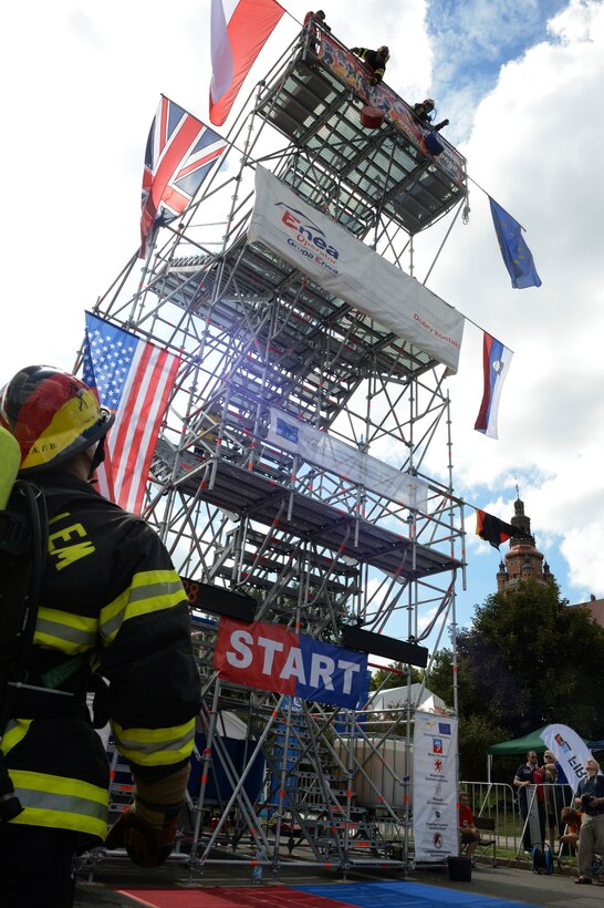 SPANGDAHLEM AIR BASE, Germany – U.S. Air Force Airman 1st Class Scott Weeks, a 52nd Civil Engineer Squadron firefighter from Green Bay, Wis., looks on as his team member Gerd Mueller, 52nd CES firefighter crew chief from Gransdorf, Germany, hoists a 40-pound weight at the annual Szczecin Firefighter Combat Challenge competition in Szczecin, Poland, Aug. 9, 2013. Hoisting the weight simulates pulling tools or an additional hose from a building roof needed to combat a real fire. (U.S. Air Force photo by Staff Sgt. Christopher Ruano/Released)