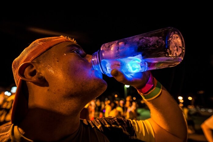 Petty Officer 3rd Class Chad Roslak, Nuclear Power Training Unit student, drinks from his water bottle that has a non-toxic Glow-in-the-dark accessory in it after finishing the Nuclear Glow 5K Aug. 9, 2013, at Joint Base Charleston – Weapons Station, S.C. Service members and their families ran through base housing wearing glow-in-the-dark clothing and accessories. (U.S. Air Force photo/ Senior Airman Dennis Sloan)