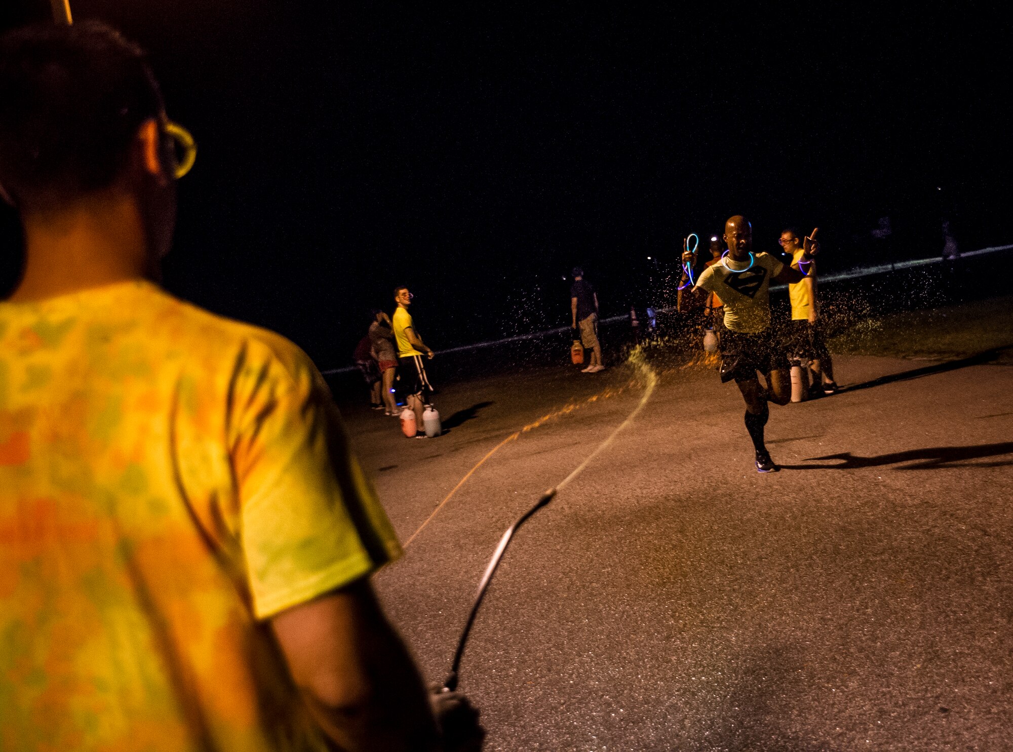 Service members and their families are sprayed with a glow in the dark liquid at the end of the Nuclear Glow 5K Aug. 9, 2013, at Joint Base Charleston – Weapons Station, S.C. The race was hosted by the 628th Force Support Squadron to promote fitness. (U.S. Air Force photo/ Senior Airman Dennis Sloan)