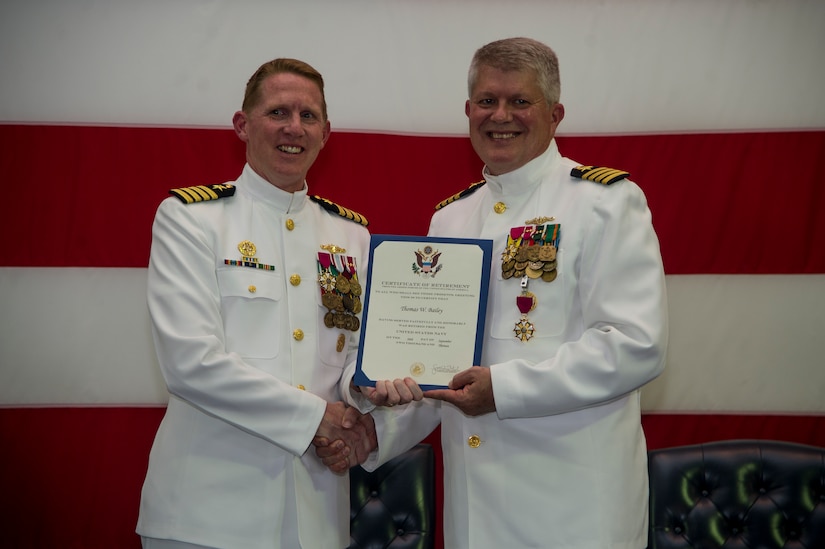 Navy Capt. Robert Hudson, Nuclear Power Training Unit commanding officer, presents a retirement certificate to Capt. Thomas Bailey, Joint Base Charleston deputy commander and former Naval Weapons Station commanding officer Aug. 9, 2013, aboard the USS Yorktown (CV 10) at Patriots Point Naval and Maritime Museum, Mount Pleasant, S.C. Bailey served more than 30 years in the U.S. Navy. (U.S. Air Force photo/Tech. Sgt. Rasheen Douglas)