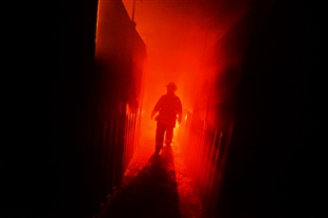 A airman walks down a hallway towards the flames during training at the Suffolk County Fire Academy in Yaphank, N.Y., Aug. 6, 2013. The airman is a firefighter assigned to the New York Air National Guard's 106th Rescue Wing on Gabreski Air National Guard Base in Westhampton Beach, NY. The firefighters reviewed basic skills in a realistic training environment under the eye of civilian firefighter trainers.