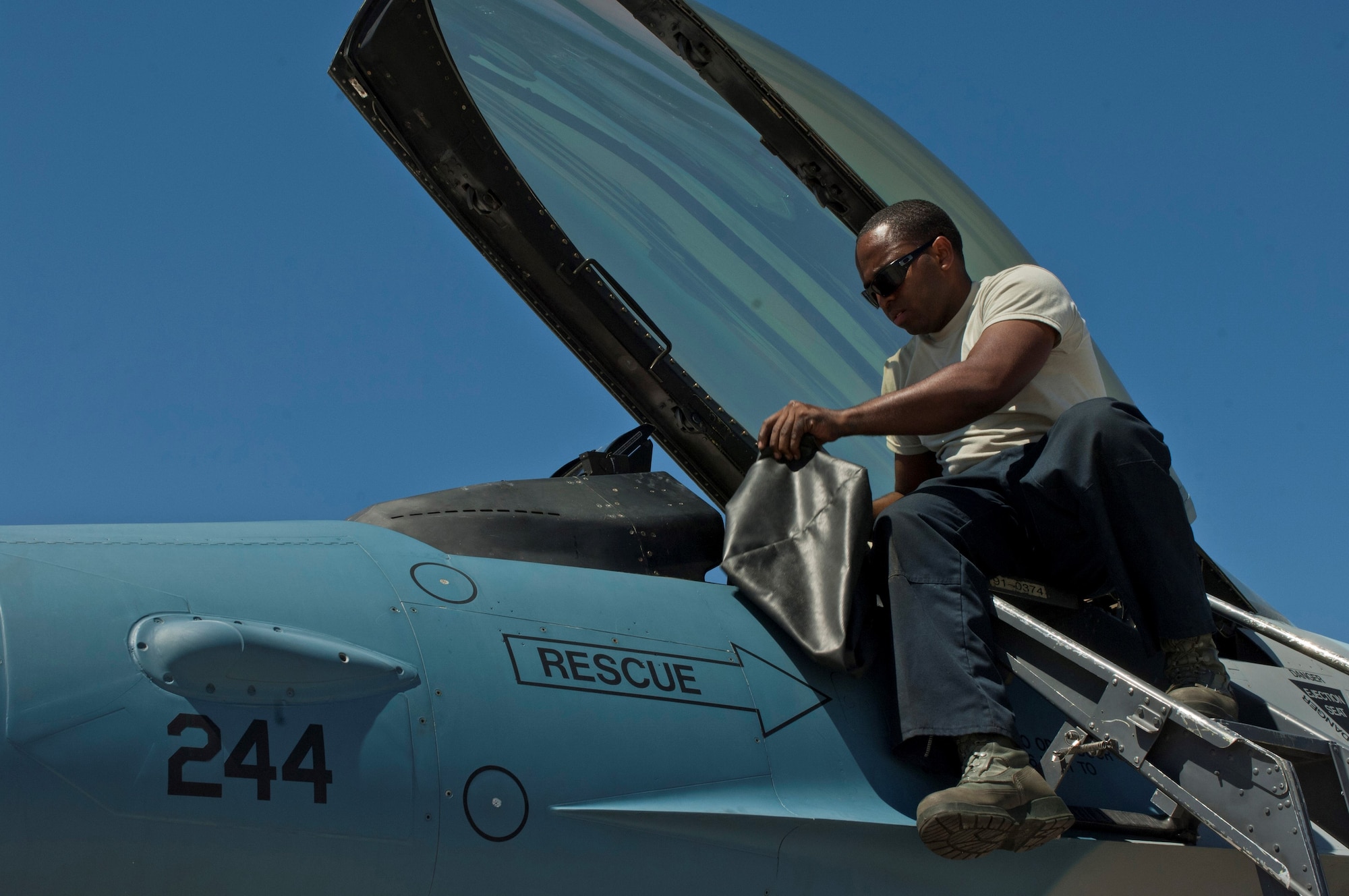 Staff Sgt. Terrance Harris prepares a 64th Aggressor Squadron F-16 Fighting Falcon cockpit before a training flight Aug. 13, 2013, at Nellis Air Force Base, Nev. Before each flight, the crew chief prepares the cockpit and ensures the pilot is strapped in safely. Harris is a crew chief assigned to the 57th Maintenance Squadron. (U.S. Air Force photo/Airman 1st Class Joshua Kleinholz)

