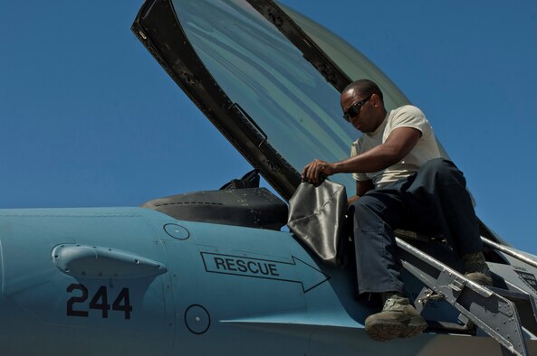 Staff Sgt. Terrance Harris prepares a 64th Aggressor Squadron F-16 Fighting Falcon cockpit before a training flight Aug. 13, 2013, at Nellis Air Force Base, Nev. Before each flight, the crew chief prepares the cockpit and ensures the pilot is strapped in safely. Harris is a crew chief assigned to the 57th Maintenance Squadron. (U.S. Air Force photo/Airman 1st Class Joshua Kleinholz)

