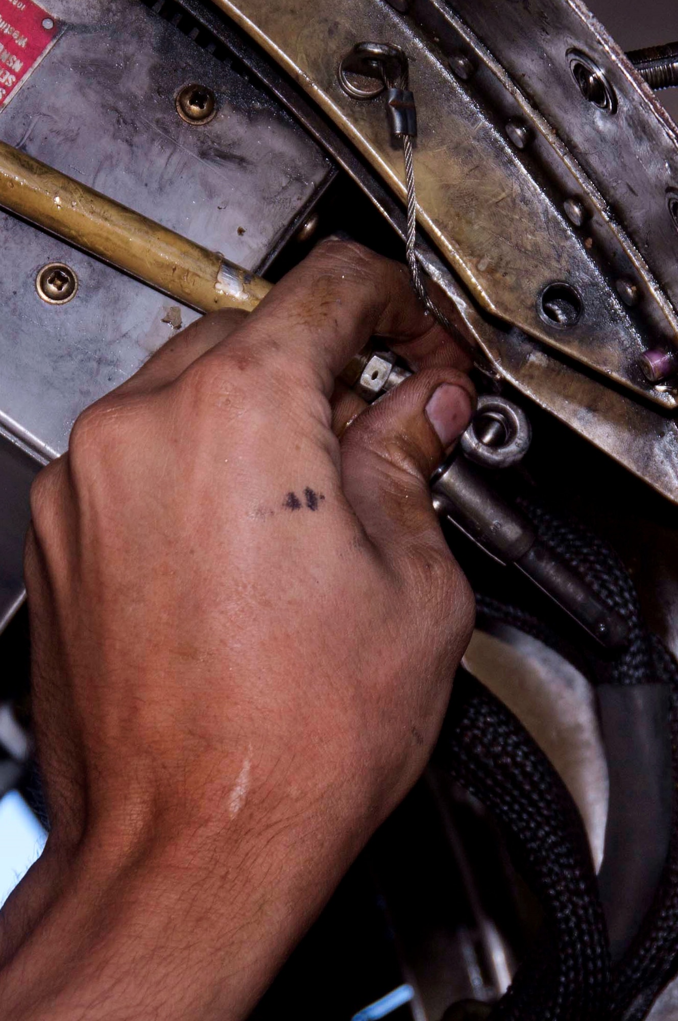 Staff Sgt. Evan Ciemnoczolowski latches a bar in place to hold up a panel on an F-16 Fighting Falcon assigned to the 64th Aggressor Squadron Aug. 13, 2013, at Nellis Air Force Base, Nev. Crew chiefs are responsible for inspecting aircraft and fixing any discrepancies noticed during pre or post flight inspections. Ciemnoczolowski is a crew chief assigned to the 57th Aircraft Maintenance Squadron. (U.S. Air Force photo/ Airman 1st Class Timothy Young)
