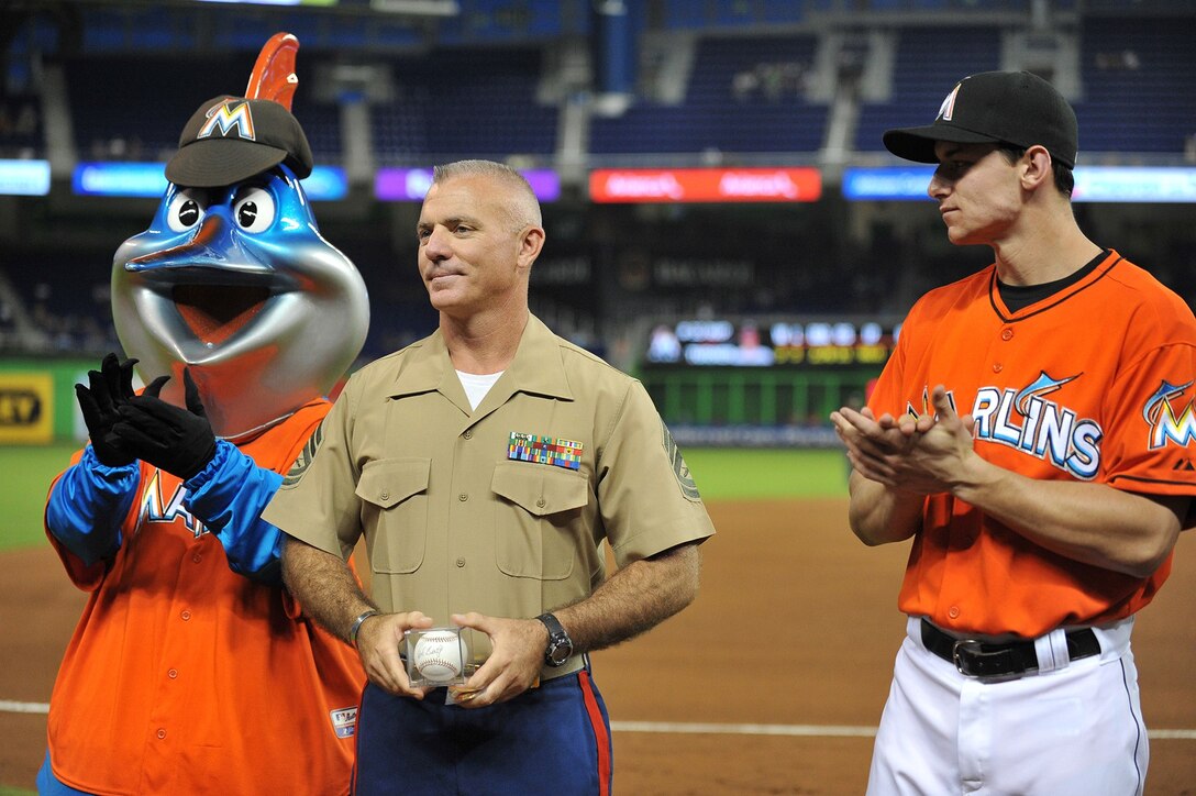 Gunnery Sgt. Kevin Kozma, the force deployment chief for U.S. Marine Corps Forces South, accepts a baseball during a pre-game ceremony as part of the Marlins Military Mondays. The Marlins mascot, Billy, along with catcher Rob Brantly, presented Kozma the award to honor his dedicated service to country and community. (Photo courtesy of the Miami Marlins, Photo by Robert Vigon)    