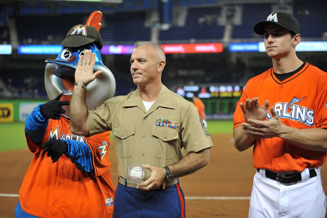 Gunnery Sgt. Kevin Kozma, the force deployment chief for U.S. Marine Corps Forces South, waves to the crowd after accepting a baseball during a pre-game ceremony as part of the Marlins Military Mondays. The Marlins mascot, Billy, along with catcher Rob Brantly, presented Kozma the award to honor his dedicated service to country and community. (Photo courtesy of the Miami Marlins, Photo by Robert Vigon)   