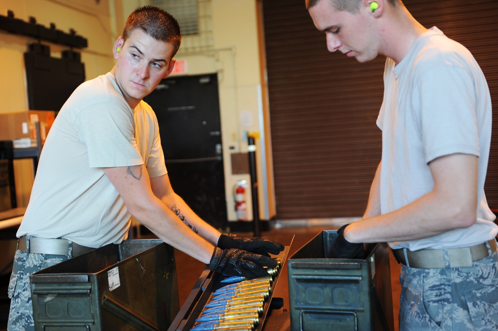 U.S. Air Force Senior Airman Ben Staples, left, 35th Maintenance Squadron munitions crew chief, and Airman 1st Class Tyler Peterson, 35 MXS munitions crew member, load 20mm rounds on to a Universal Ammunition Loading System at Misawa Air Base, Japan, Aug. 14, 2013. The ammo is used with M61 gun systems on F-16 Fighting Falcons, which are often employed during exercises at Draughon Range outside of Misawa AB.  (U.S. Air Force photo by Senior Airman Kia Atkins)