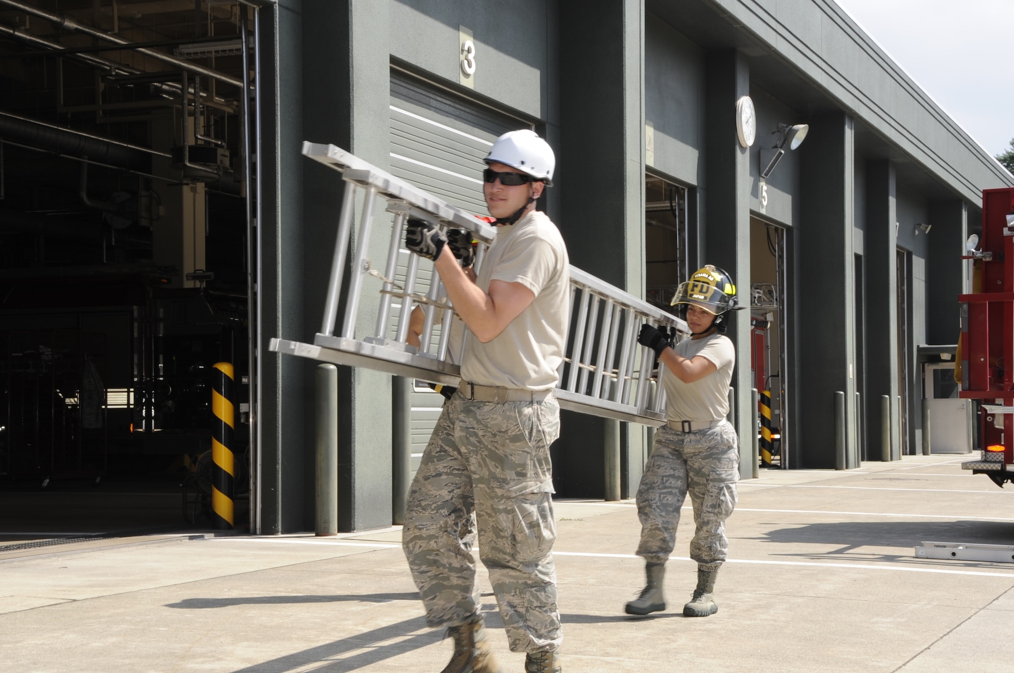 U.S. Air Force Senior Airman Justin Najarian, left, and Airman 1st Class Hillary Brock, 35th Civil Engineer Squadron firefighters, use teamwork to lift an extension ladder at Misawa Air Base, Japan, Aug. 12, 2013. Although simple in theory, ladders can cause many injuries for firefighters if not properly used, which is why training is essential. (U.S. Air Force photo by Airman 1st Class Kaleb Snay)