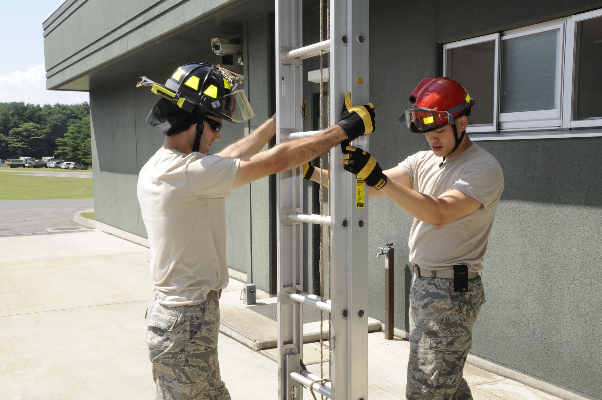 U.S. Air Force Staff Sgt. David Larose, left, and Staff Sgt. Bao Hoang, 35th Civil Engineer Squadron firefighters, demonstrate proper teamwork for handling an extension ladder at Misawa Air Base, Japan, Aug. 12, 2013. There are many dangers involved with climbing an extension ladder, which is why teamwork is essential.  (U.S. Air Force photo by Airman 1st Class Kaleb Snay)