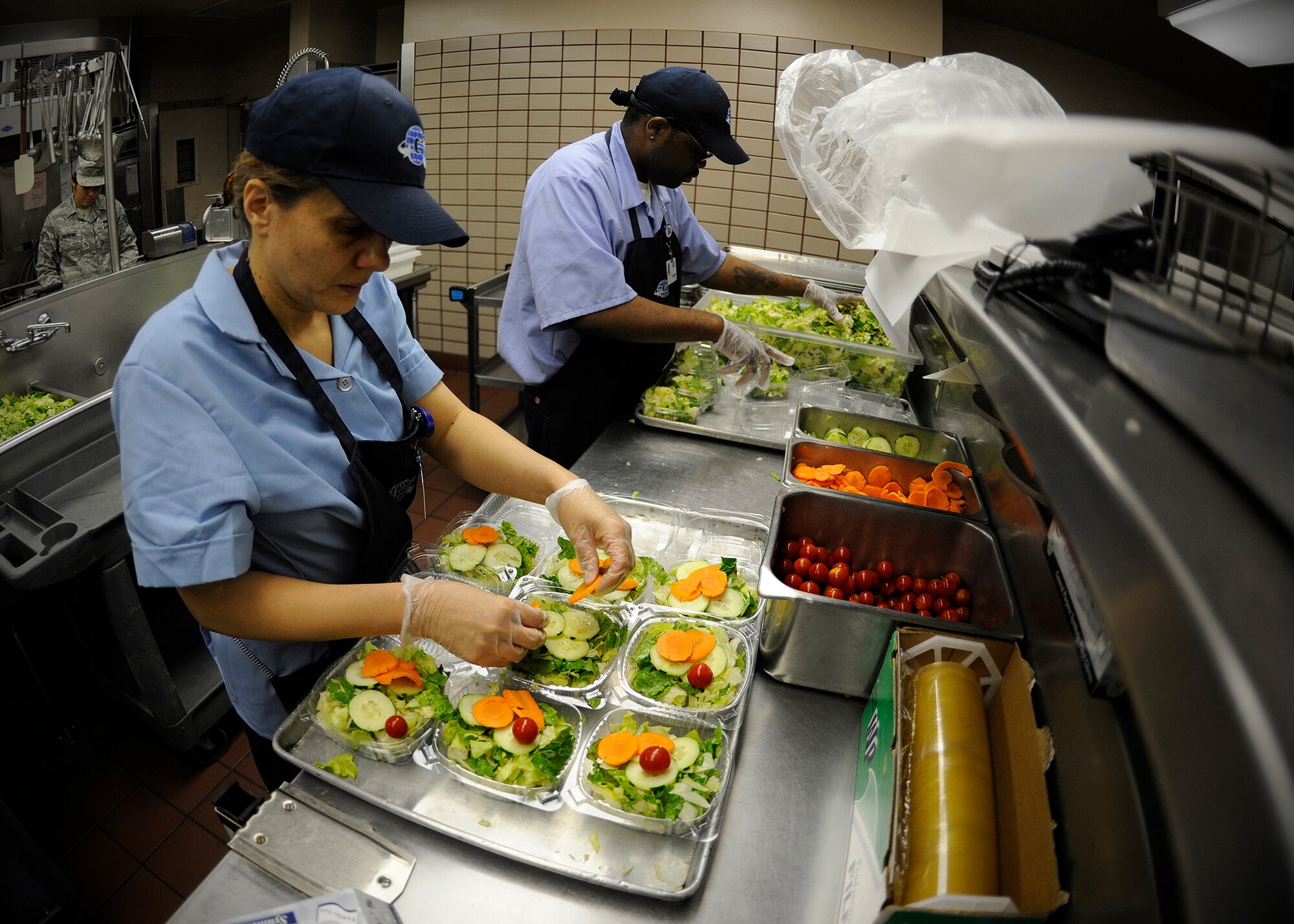 Jeannette Guin and Shaun Jones, 354th Force Support Squadron contracted food service workers, prepare boxed salads prior to the lunch rush during RED FLAG-Alaska 13-3 at the Two Seasons Dining Facility Aug. 15, 2013, Eielson Air Force Base, Alaska. During RF-A 13-3, food preparation workers will prepare more than 700 salads each day. (U.S. Air Force photo by Senior Airman Shawn Nickel/Released)