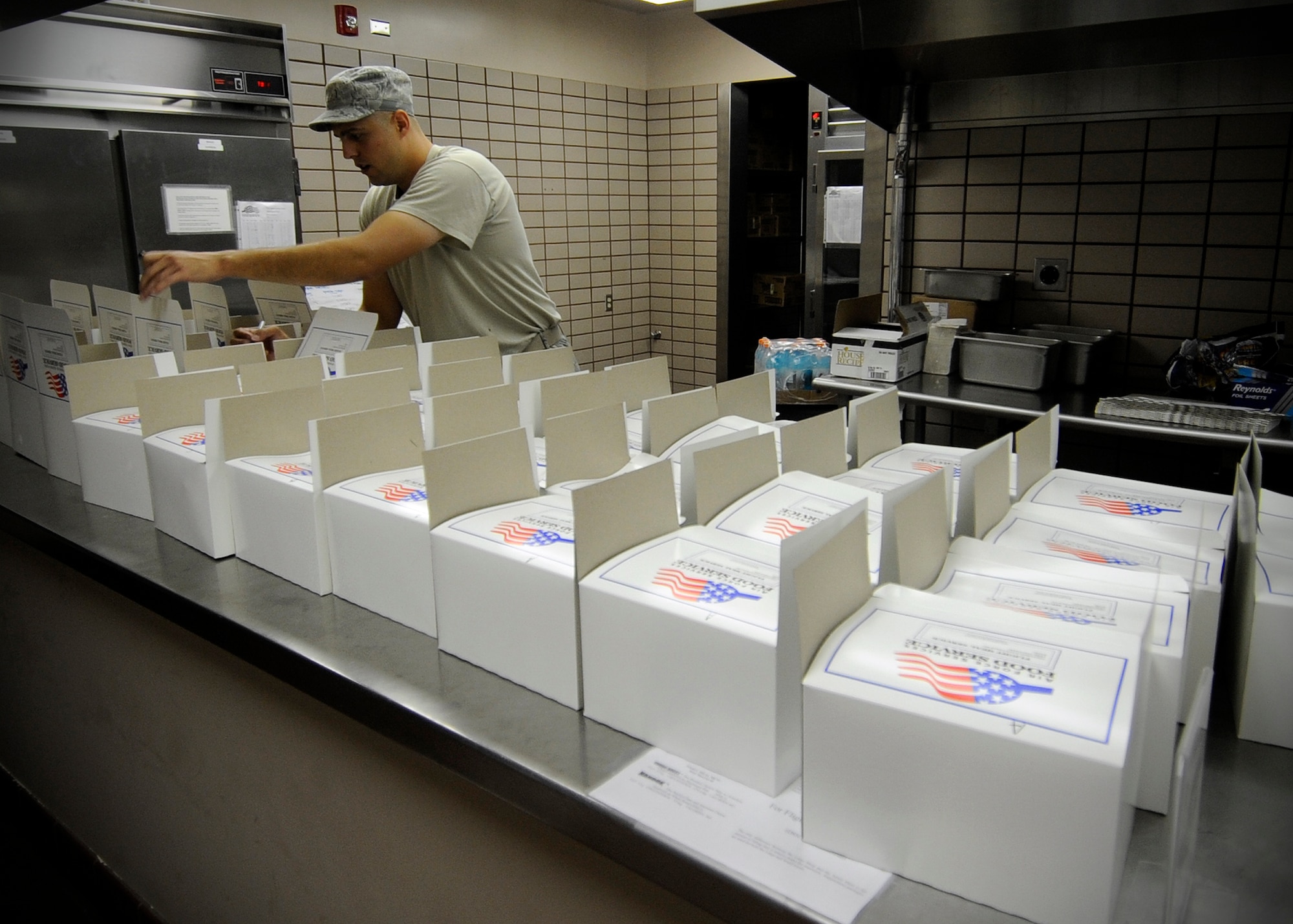 Staff Sgt. Shaun Collette, 354th Force Support Squadron NCO in charge of the flight kitchen, prepares box lunches during RED FLAG-Alaska 13-3 at the Two Seasons Dining Facility Aug. 15, 2013, Eielson Air Force Base, Alaska. The DFAC assembles more than 250 boxed meals throughout each day to nourish service members who can’t make regular meals. (U.S. Air Force photo by Senior Airman Shawn Nickel/Released)
