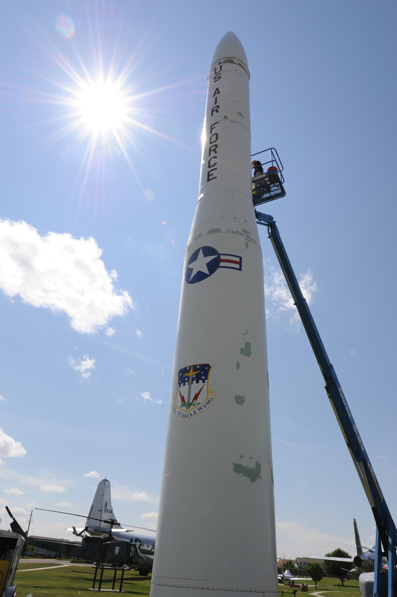 Workers use sheet metal to repair some of the damage on a Minuteman III missile static display. The exhibits being restored outside the museum are a 1942 Ford staff car, two Minute Man missiles (one on display in front of building 1191,) a transporter erector trailer and a UH-1F helicopter. (U.S. Air Force photo/Airman 1st Class Collin Schmidt)