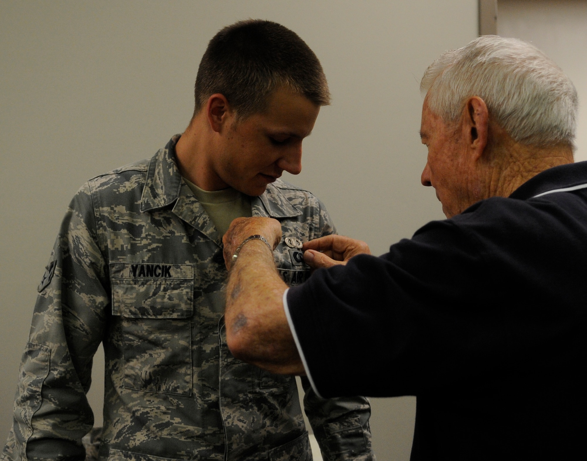 Former Chief Master Sgt. of the Air Force Robert Gaylor pins the air traffic control occupational badge on Airman 1st Class Austin Yancik at Whiteman Air Force Base, Mo., Aug. 8, 2013. The badge signifies that Yancik, an air traffic control journeyman in the 509th Operation Support Squadron, is now certified to conduct air traffic without supervision. (U.S. Air Force photo by Staff Sgt. Alexandra M. Boutte/Released)