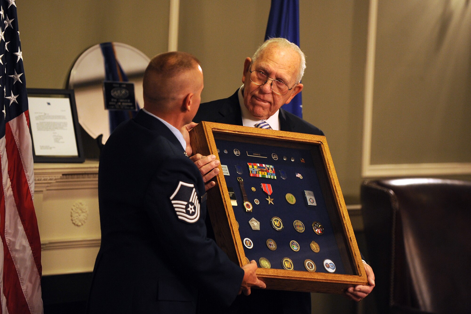 James Norwood, an electronic intelligence advisor with the National Security Agency’s representative office at United States Strategic Command, receives a shadow box from U.S. Air Force Master Sgt. William Bonen, superintendent cryptologic service group with USSTRATCOM, at a retirement ceremony held at the Patriot Club July 31 on Offutt Air Force Base, Neb.  The nearly 60 years of combined enlisted and civil service medals and trinkets adorned the shadow box which is usually given to military retirees.  (U.S. Air Force photo by Josh Plueger/Released)