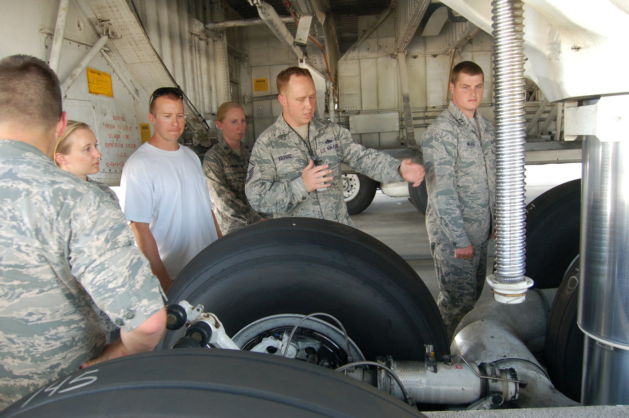 Master Sgt. Tim Kilford, a 433rd Aircraft Maintenance Squadron day shift supervisor, explains the uniquely complex landing gear mechanism to nine graduates of Wilford Hall Medical Center’s year-long clinical psychology program here Aug. 15.  The recent graduates visited the “Alamo Wing” to learn more about ramp operations of a unit-equipped installation. Upon their reassignments they will be better able to understand andassist troops who work in similar, operational environments.   (U.S. Air Force photo by Elsa Martinez)