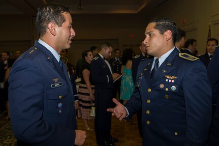 Capt. Carlos Monroy (left), Colombia air force internal control offi cer, talks with Capt. Daniel Yapor, Dominican Republic air force pilot, after the Inter-American Air Forces Academy graduation banquet July 31. Monroy and Yapor met through the IAAFA  International Squadron Officers School Professional Military Education class at Joint Base San Antonio-Lackland.