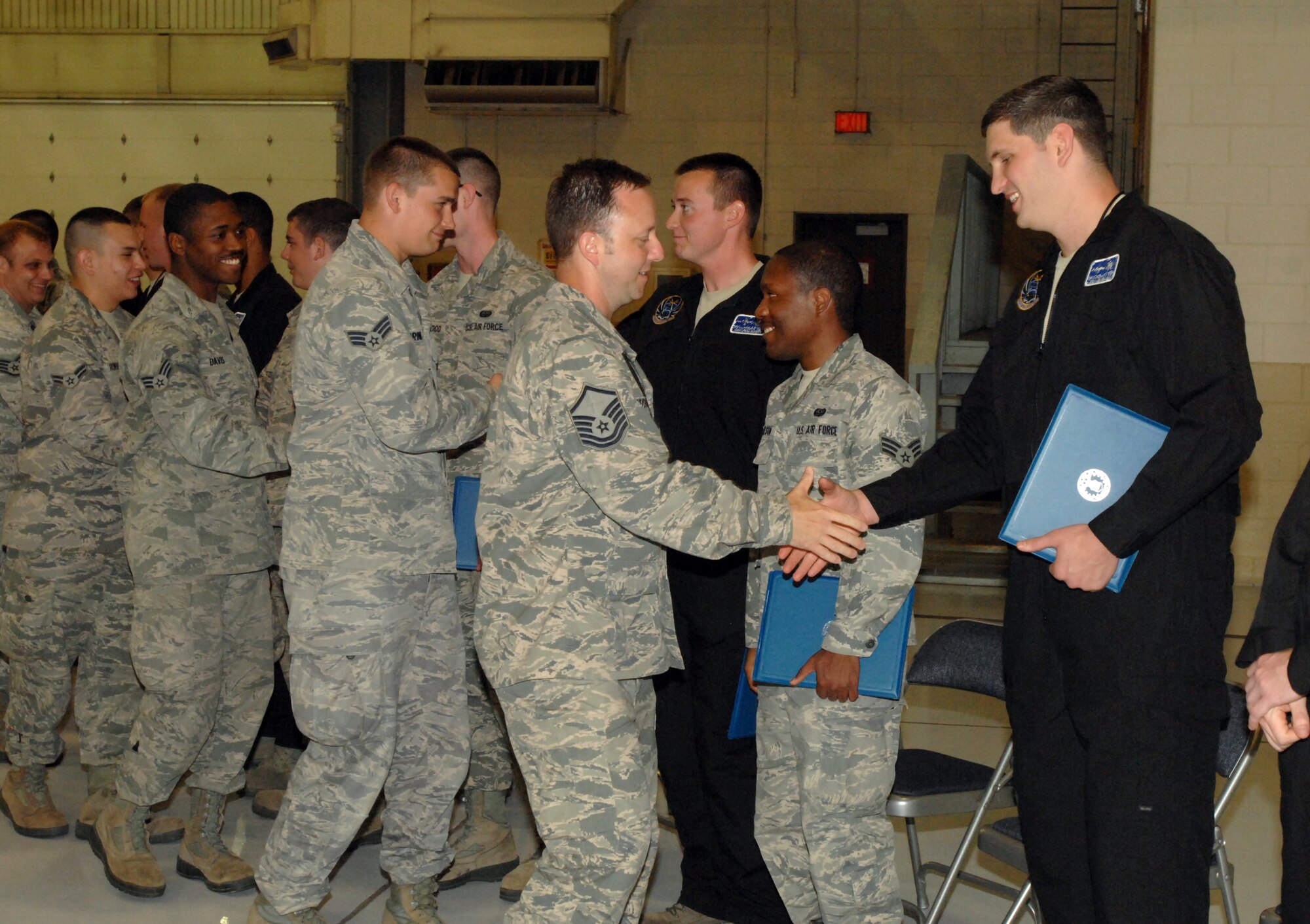 Members of the 69th Reconnaissance Group congratulate more than a dozen crew chiefs from the 69th Maintenance Squadron, who received their distinctive black coveralls after earning their new titles of dedicated crew chiefs (DCC) during a special ceremony, which took place Aug. 5, 2013, in one of the hangars at Grand Forks Air Force Base, N.D. The title of DCC and the black coveralls officially acknowledges that an individual is a maintenance expert on their respective aircraft. (U.S. Air Force photo/Staff Sgt. Susan Davis)