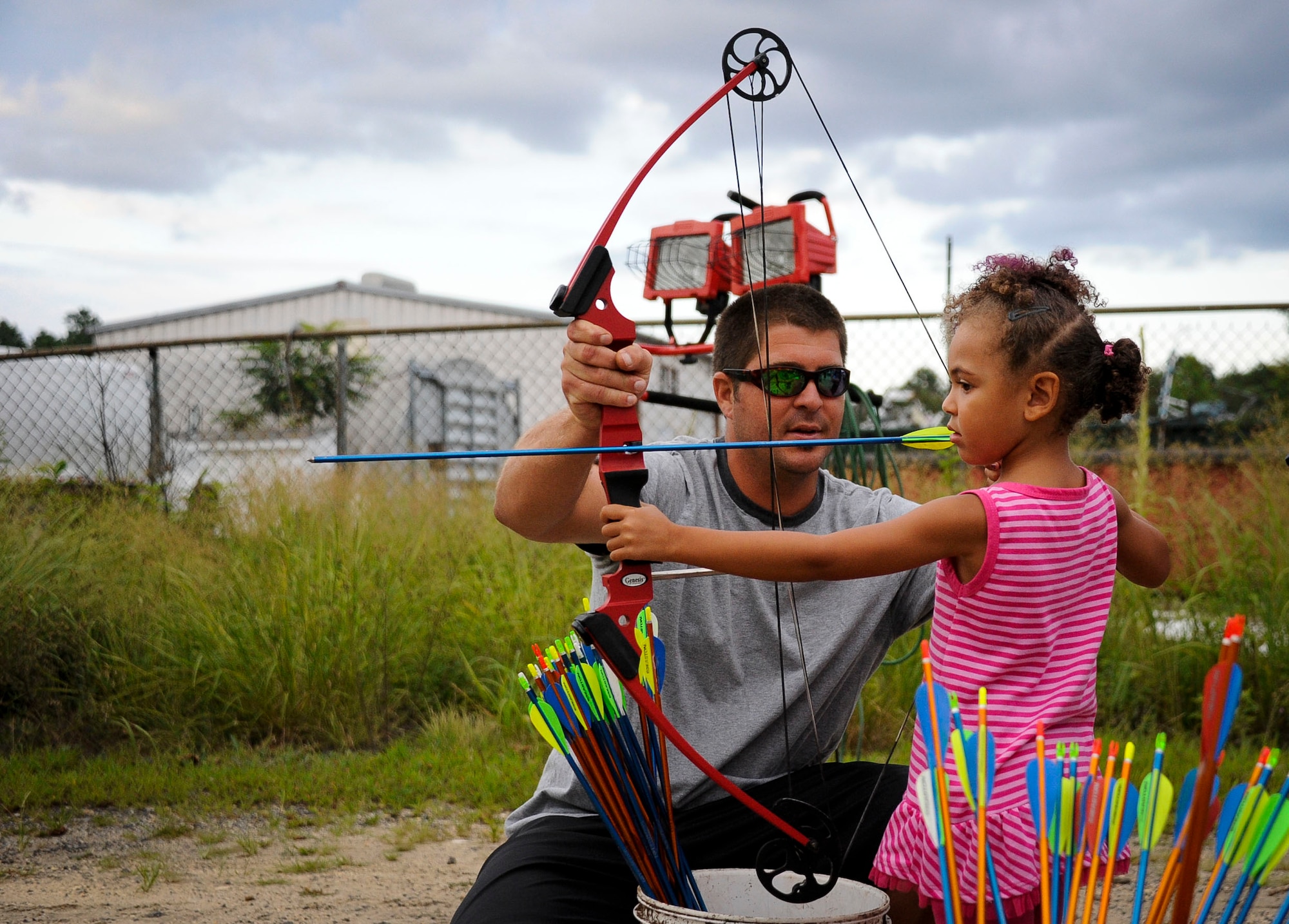 Nathan Figley, N.J. Fish and Wildlife Service employee, helps Gianna Mendoza, 4, shoot a bow and arrow at the National Night Out event Aug. 6, 2013, in Lakehurst, N.J. Local businesses, state organizations and emergency responders were all present to show support for the national crime prevention initiative. (U.S. Air Force photo By Airman 1st Class Ryan Throneberry/Released)