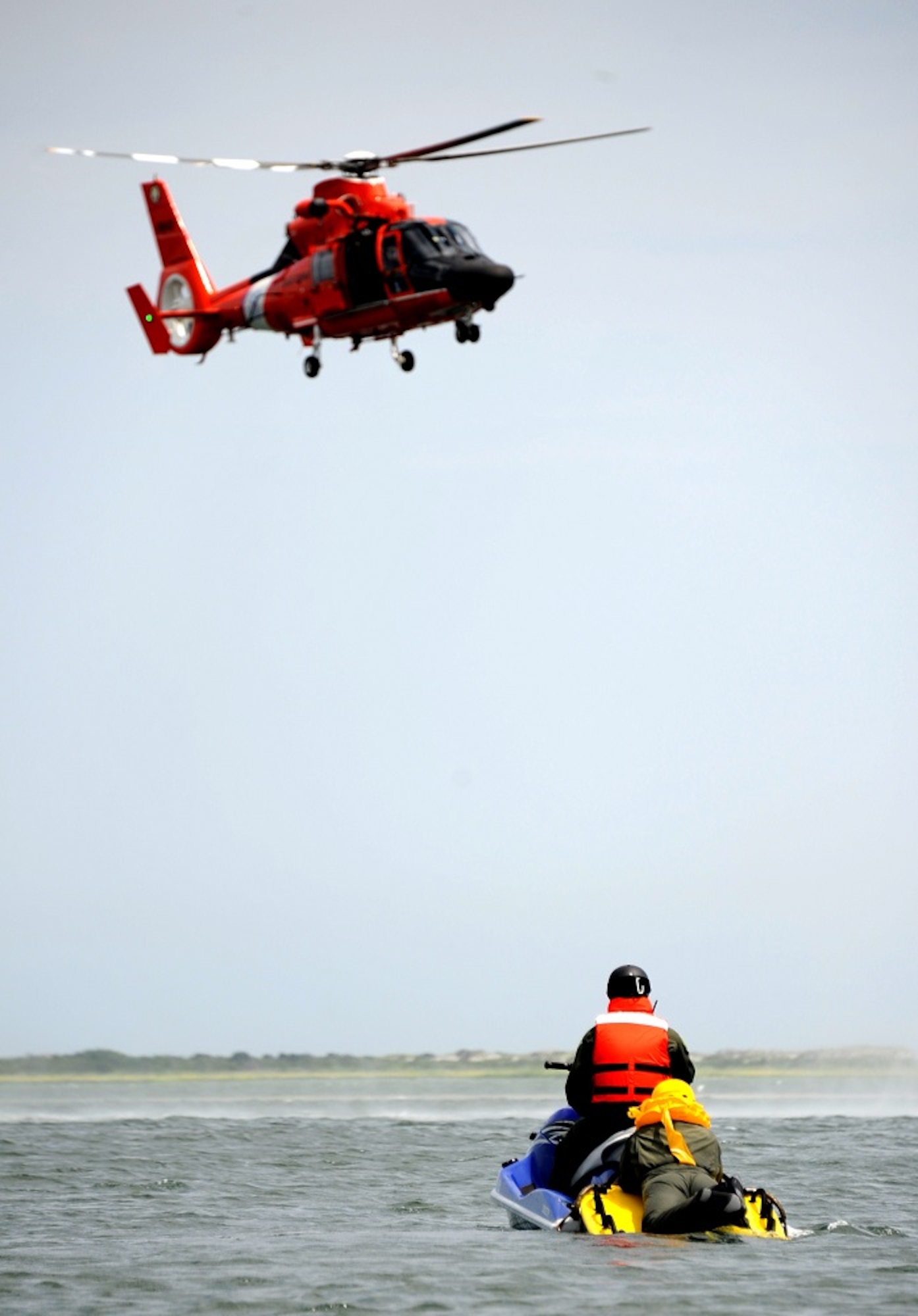 An aircrew member prepares to enter the hoist basket of an H-65 Dolphin rescue helicopter with the help of a Coast Guard rescue swimmer during a Survival, Evasion, Resistance and Escape water survival class Aug. 8, 2013, at Long Beach Island, N.J. The Coast Guard swimmer rescued 14 aircrew members during the simulated rescue mission. (U.S. Air Force photo by Airman 1st Class Sean M. Crowe/Released)