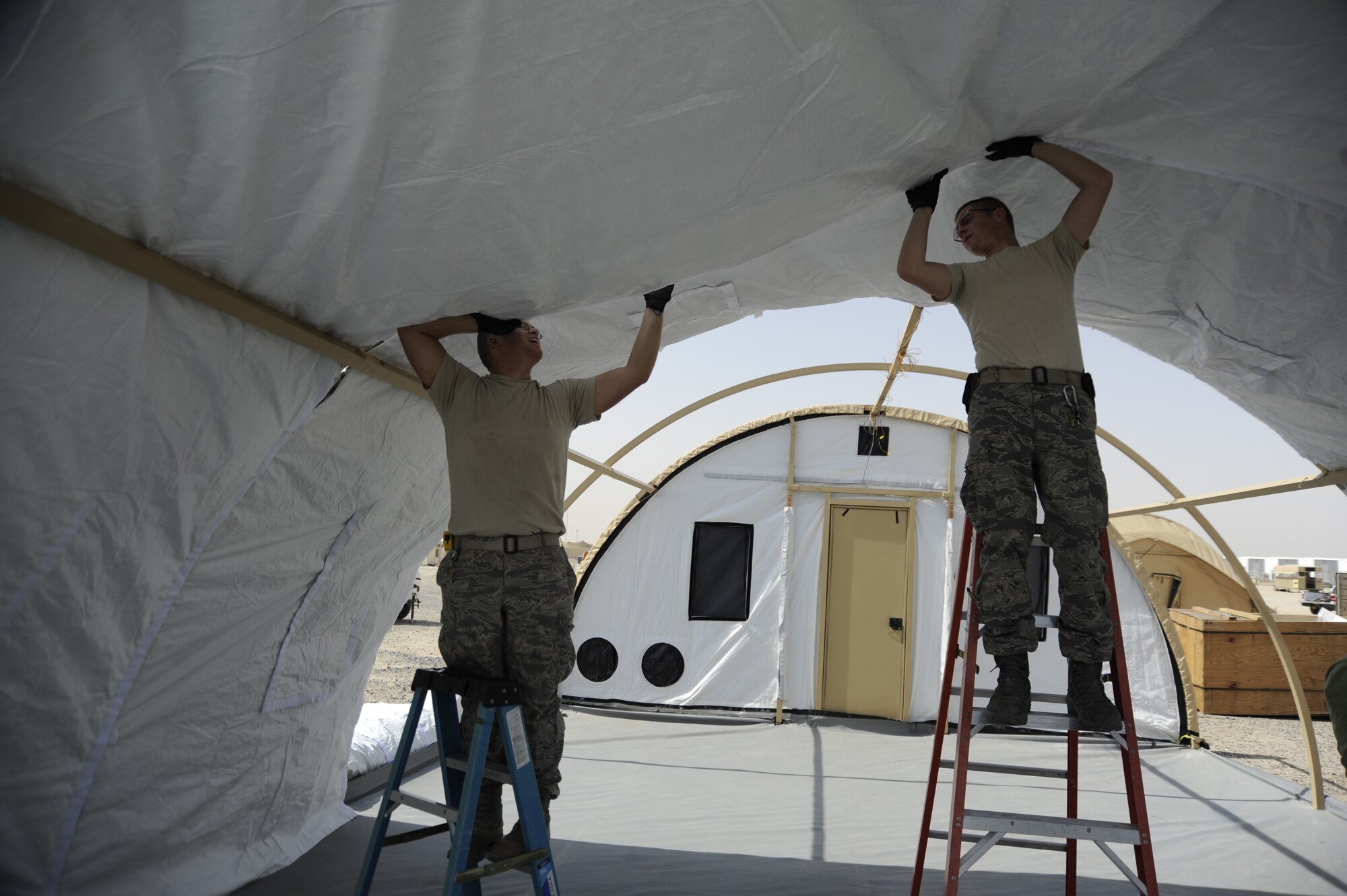 SOUTHWEST ASIA -- Two Airmen install an insulated liner into a new tent at a base here. The liner is just one of the new technologies being tested in the AOR in a joint project with the Air Force and the Army to reduce the energy used in expeditionary settings.  (U.S. Air Force photo/Master Sgt. Christopher Campbell)