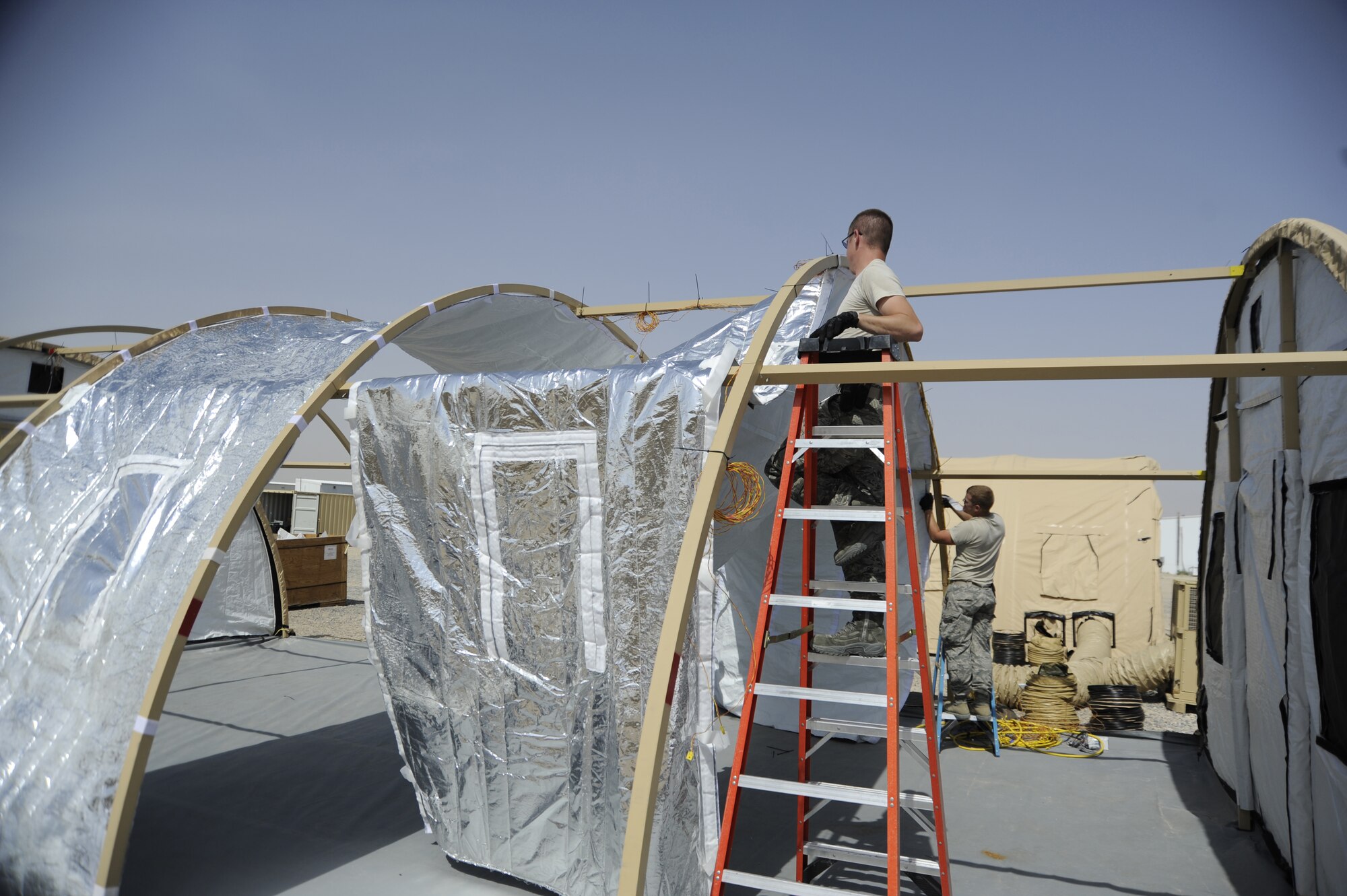 SOUTHWEST ASIA -- Airmen at a base here erect special tents equipped with new energy-saving technologies. The tents equipped with photovoltaic flys, insulated liners and more efficient environmental control units are being monitored in the harsh desert conditions to see how effective they are at saving energy. (U.S. Air Force photo/Master Sgt. Christopher Campbell)