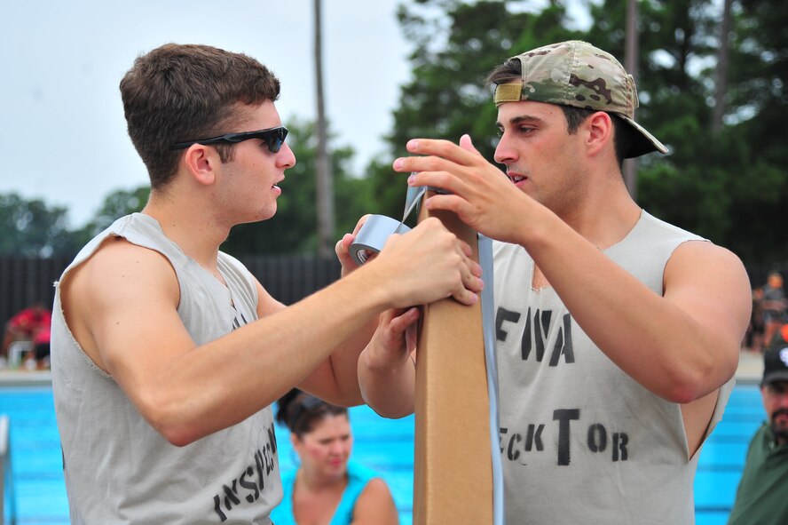 U.S. Air Force Airman 1st Class Matthew Duff, 4th Civil Engineer Squadron Explosives Ordnance Disposal (EOD) apprentice, discusses boat-building strategies with Senior Airman Justin Beasley, 4th CES EOD craftsman, as they duct tape cardboard during a Build-a-Boat competition at Seymour Johnson Air Force Base, N.C., Aug. 14, 2013. After an hour of building, teams raced the length of the base pool competing for overall winner, best dressed and best chant. (U.S. Air Force photo by Senior Airman Aubrey White/Released)