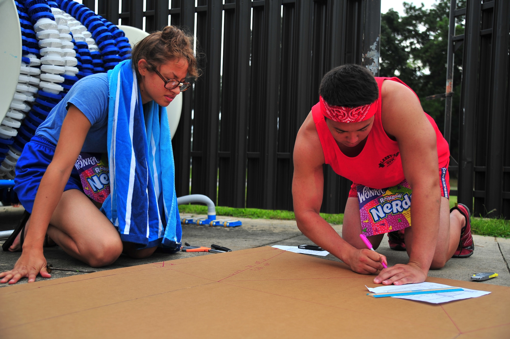 U.S. Air Force 1st Lt. Thomas Baker, 4th Communications Squadron plans and programs officer, draws guidelines on cardboard as Airman 1st Class Rosa Morales, 4th CS knowledge operations manager, watches during the Build-a-Boat competition at Seymour Johnson Air Force Base, N.C., Aug. 14, 2013. Participants were given an hour to build a boat made of cardboard and duct tape, then race it across the base pool. (U.S. Air Force photo by Senior Airman Aubrey White/Released)