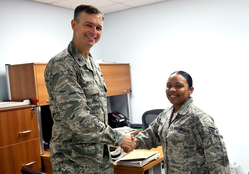 Col. Craig Wills, 39th Air Base Wing commander, presents a coin to Senior Airman Natasha Hannibal, 39th Medical Support Squadron medical technician, Aug. 15, 2013, at Incirlik Air Base, Turkey. Hannibal was awarded for her hard work and dedication to Incirlik Airmen and family members. (U.S. Air Force photo by Senior Airman Daniel Phelps/Released)