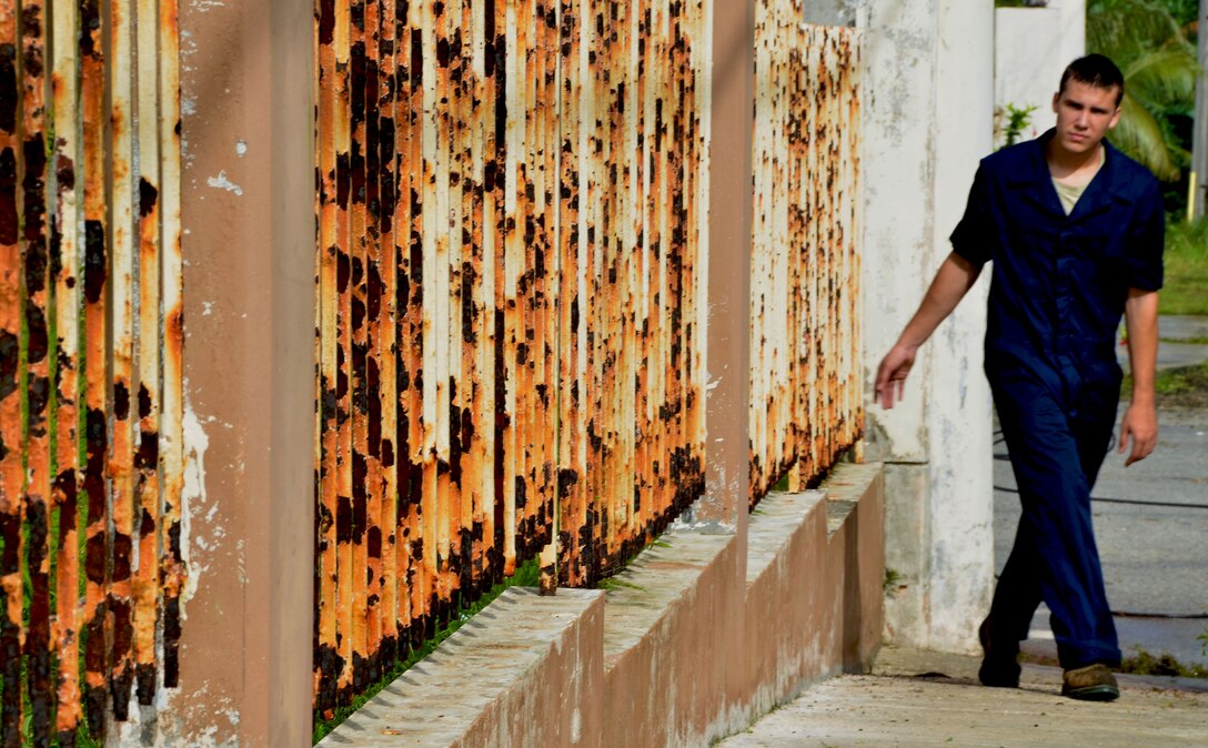 YIGO, Guam—Airman 1st Class David Hall, 36th Civil Engineer Squadron electrical power production technician, checks an outer fence for loose debris during a school beautification project at the Machananao Elementary School in Yigo, Guam, Aug. 14, 2013. Volunteers from Andersen Air Force Base joined forces with U.S. Army units to clean up debris, pressure-wash and repaint the walls, fence and entrance ways of Machananao Elementary before students return from summer break.  (U.S. Air Force photo by Staff Sgt. Benjamin Wiseman/Released)