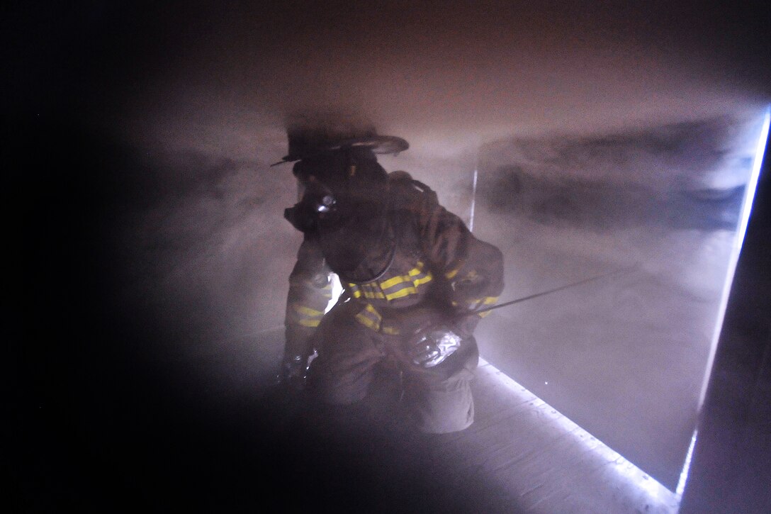 An airman enters a smokefilled room in a simulated burning building